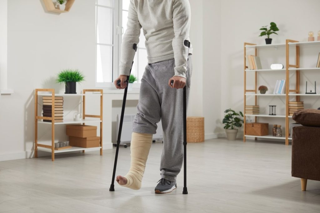 Person With A Leg In A Cast Walking On Crutches In A Cozy Living Room.